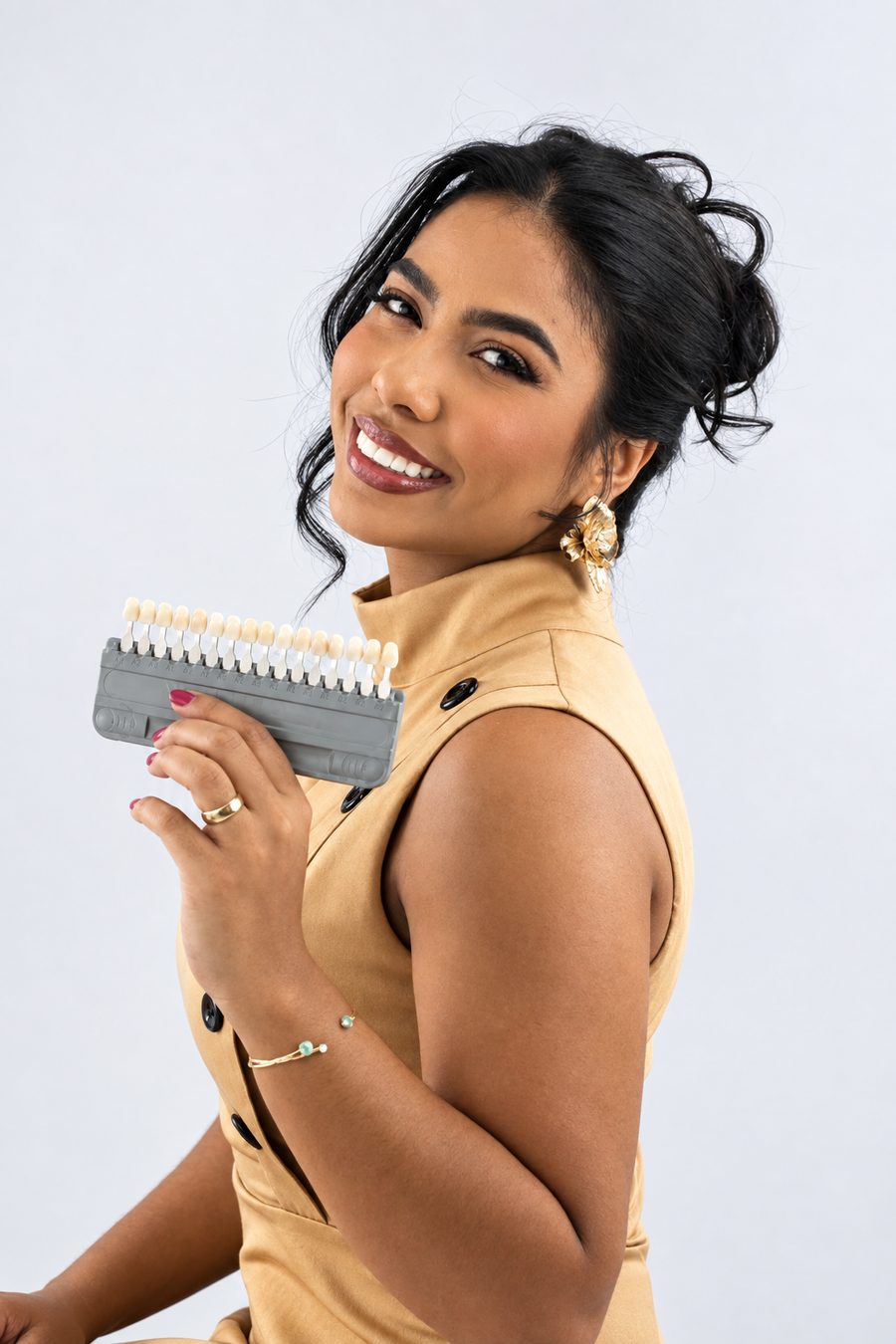 Dra. Danile Jandiroba sorrindo, segurando uma escala de cores de dentes